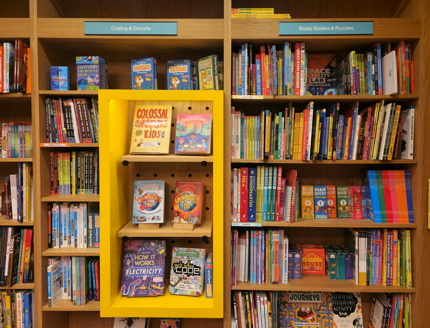 Children's educational books and games on a wooden bookshelf display.