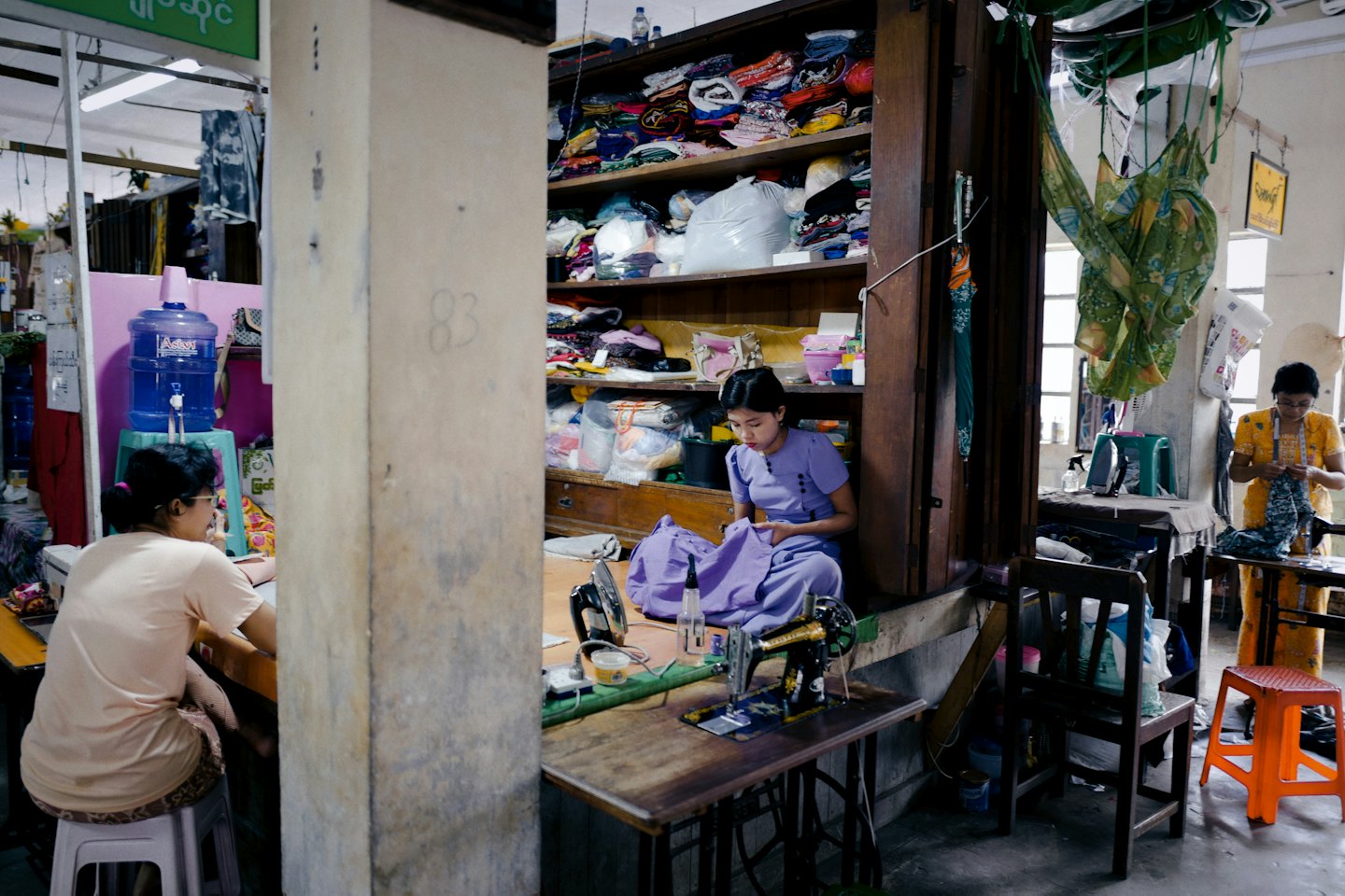 Women sewing and tailoring garments in a busy workshop.